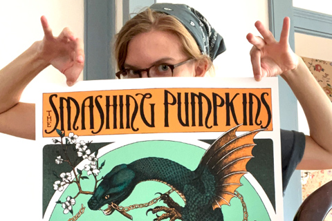 Kelly holding up a Smashing Pumkins poster that she designed.